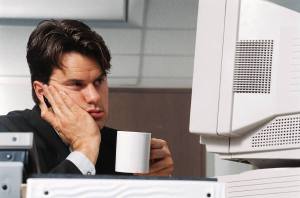 Man sitting in front of a computer with a bored expression